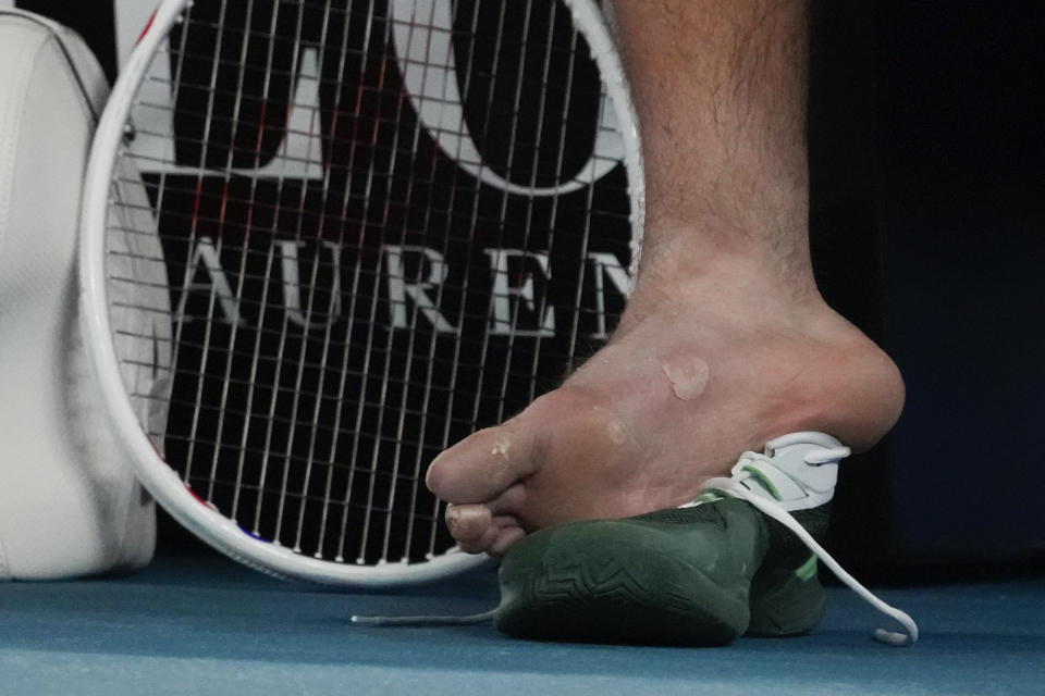 Daniil Medvedev of Russia takes his shoe off to have a blister attended to during his second round match against Emil Ruusuvuori of Finland at the Australian Open tennis championships at Melbourne Park, Melbourne, Australia, Friday, Jan. 19, 2024. (AP Photo/Andy Wong)