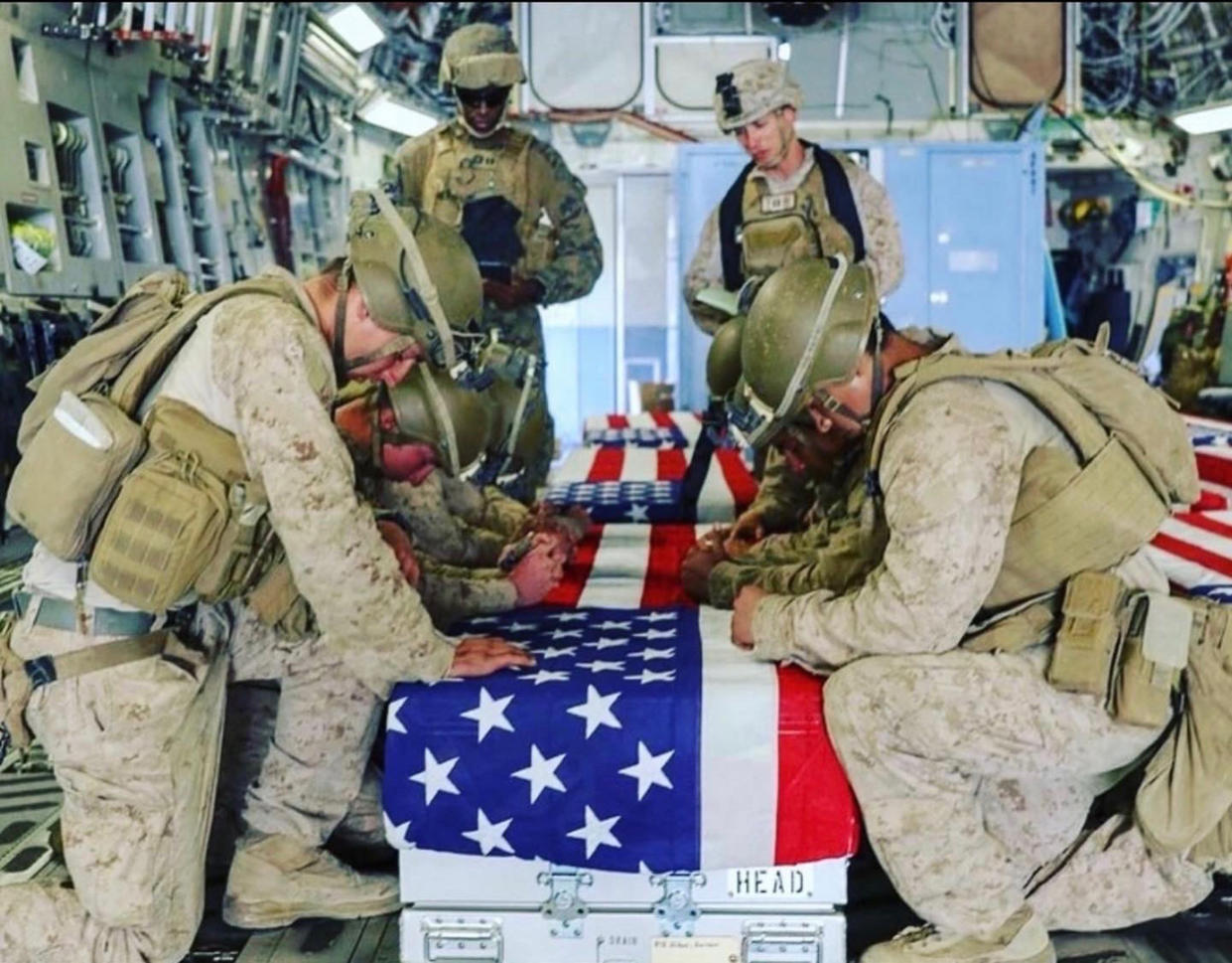 Fellow Marines kneel over the coffin of Kareem Nikoui en route to Dover Air Force Base. (Courtesy Shana Chappell)