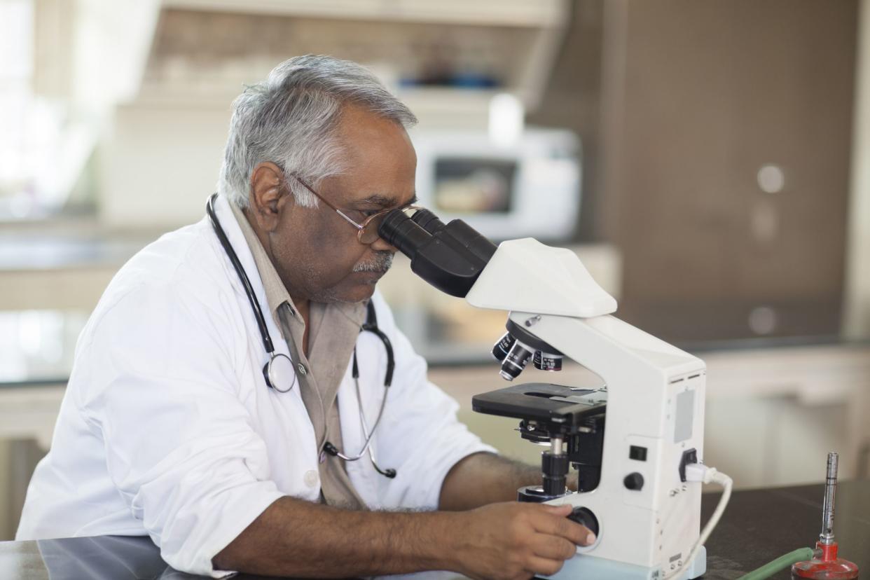Indian Doctor Looking Through Microscope, Checking Illumination in a Microscope In A Laboratory