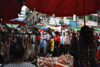 Protester flash the three-fingered salute as they march past meat vendors in Yangon, Myanmar on Sunday, Feb. 7, 2021. Thousands of people rallied against the military takeover in Myanmar's biggest city on Sunday and demanded the release of Aung San Suu Kyi, whose elected government was toppled by the army that also imposed an internet blackout. (AP Photo)