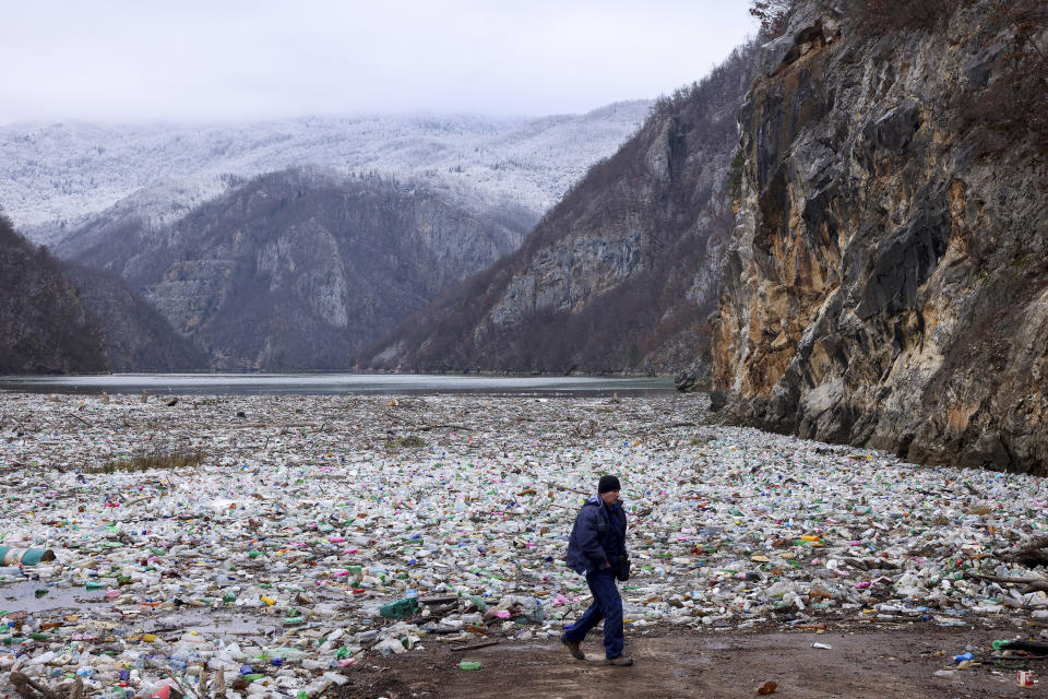 A crane operator walks next to the waste footing in the Drina river near Visegrad, Bosnia, Wednesday, Jan. 10, 2024. Tons of waste dumped in poorly regulated riverside landfills or directly into the rivers across three Western Balkan countries end up accumulating during high water season in winter and spring, behind a trash barrier in the Drina River in eastern Bosnia. (AP Photo/Armin Durgut)
