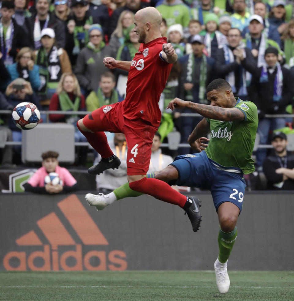 Toronto FC's Michael Bradley, left, and Seattle Sounders' Roman Torres battle for the ball Sunday, Nov. 10, 2019, during the first half of the MLS Cup championship soccer match in Seattle. (AP Photo/Elaine Thompson)