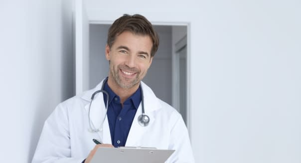 Doctor In His Office Holding A Clipboard