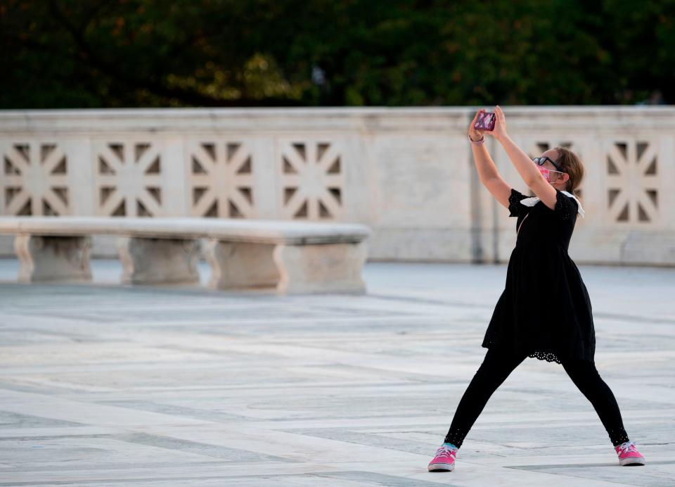 A young girl dressed as Ruth Bader Ginsburg takes a photo as the late Supreme Court Justice Ruth Bader Ginsburg lays in repose at the Supreme Court in Washington, DC.