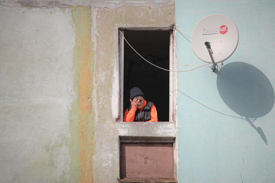 Una mujer mayor, en una ventana de una casa en una zona pobre de Bucarest, Rumanía, el 27 de marzo de 2020. En un intento por frenar la propagación del nuevo coronavirus, el gobierno decretó, entre otras medidas, que la gente mayor de 65 años no salga de su casa a excepción de en un intervalo de dos horas. (AP Foto/Vadim Ghirda)