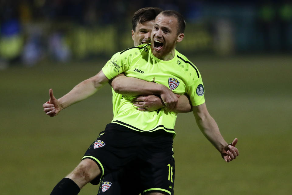 In this photo taken on Saturday, March 28, 2020, Shakhter's Sergei Balanovich, foreground, and his teammate Azdren Llullaku celebrate after scoring their side's goal during the Belarus Championship soccer match between Gorodeya and Shakhter in the town of Gorodeya, Belarus. Longtime Belarus President Alexander Lukashenko is proudly keeping soccer and hockey arenas open even though most sports around the world have shut down because of the coronavirus pandemic. The new coronavirus causes mild or moderate symptoms for most people, but for some, especially older adults and people with existing health problems, it can cause more severe illness or death. (AP Photo/Sergei Grits)