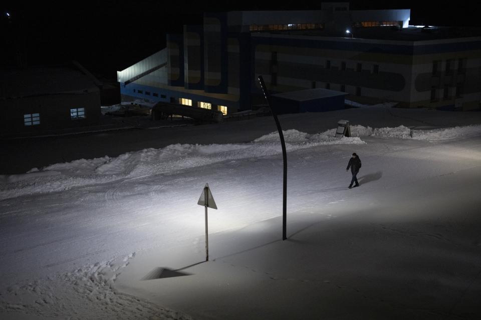A man walks down a street in Barentsburg, Norway, Saturday, Jan. 7, 2023. About 350 miners working for Russia's Arctic mining company live with their families in this village, which sits by a fjord 37 miles (60 kilometers) from Svalbard's main town of Longyearbyen. (AP Photo/Daniel Cole)