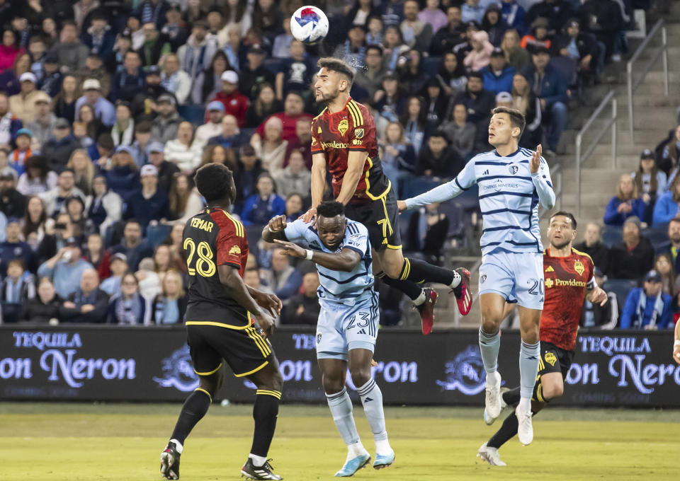 Seattle Sounders midfielder Cristian Roldan (7) heads the ball over Sporting Kansas City forward Willy Agada (23) and forward Daniel Salloi (20) during the second half of an MLS soccer match against on Saturday, March 25, 2023, in Kansas City, Kan. (AP Photo/Nick Tre. Smith)