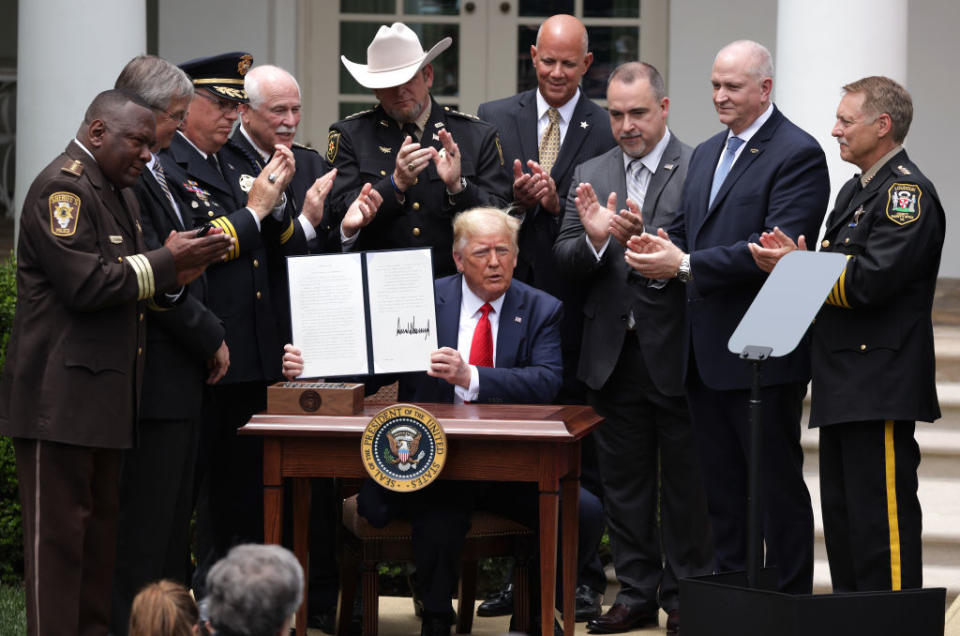 Surrounded by members of law enforcement, U.S. President Donald Trump holds up an executive order he signed on “Safe Policing for Safe Communities” during an event in the Rose Garden at the White House June 16, 2020 in Washington, DC. President Trump will signed an executive order on police reform amid the growing calls after the death of George Floyd. (Photo by Alex Wong/Getty Images)