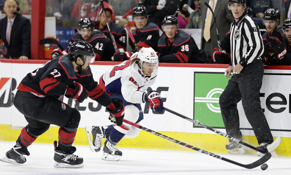 Carolina Hurricanes' Justin Faulk (27) and Washington Capitals' Carl Hagelin (62), of Sweden, chase the puck during the first period of Game 6 of an NHL hockey first-round playoff series in Raleigh, N.C., Monday, April 22, 2019. (AP Photo/Gerry Broome)