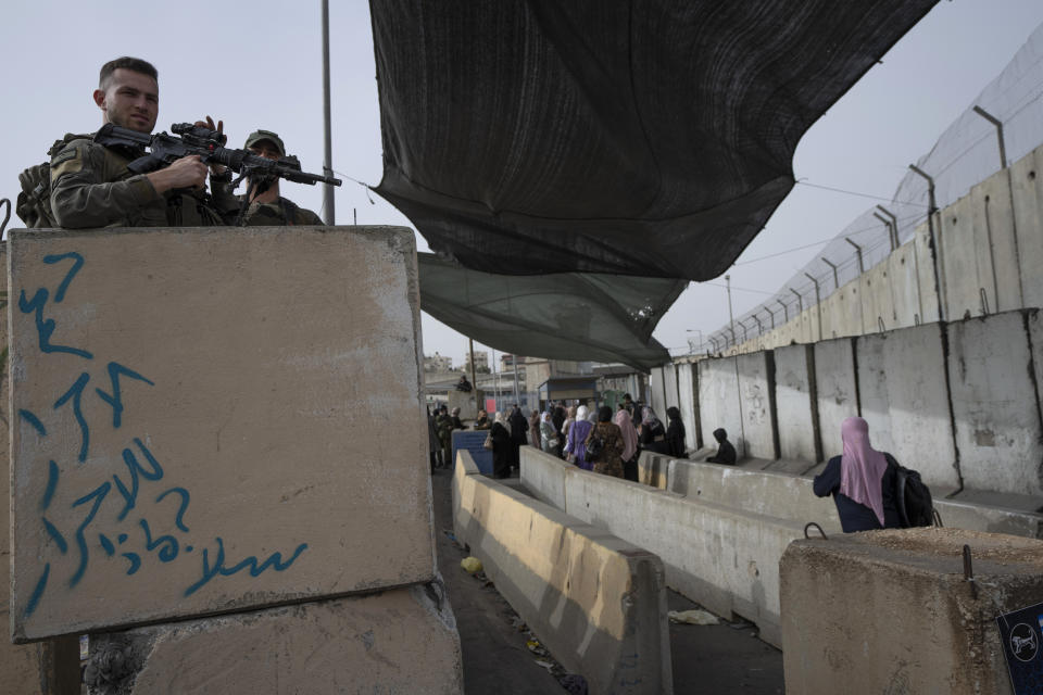 FILE - Israeli Border Police officers secure a checkpoint used by Palestinian to cross from the West Bank into Jerusalem, for the first Friday prayers in the Muslim holy month of Ramadan at the Al Aqsa mosque compound, at the Qalandia Israeli army checkpoint, west of Ramallah, April 8, 2022. The Israeli military body in charge of civilian affairs in the occupied West Bank has developed a new policy that would heavily regulate entry into the territory. (AP Photo/Nasser Nasser, File)