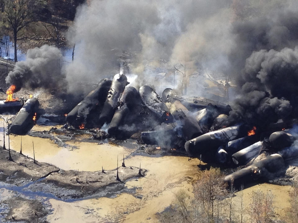 FILE- In this Nov. 8, 2013 file photo, a tanker train carrying crude oil burns after derailing in western Alabama outside Aliceville, Ala. The Trump administration vastly understated the potential benefits of installing more advanced brakes on trains that haul explosive fuels when it cancelled a requirement for railroads to begin using the equipment. A government analysis used by the administration to justify the cancellation omitted up to $117 million in potential reduced damages from using electronic brakes. Department of Transportation officials acknowledged the error after it was discovered by The Associated Press during a review of federal documents but said it would not have changed their decision. (Bill Castle/ABC 33/40 via AP, File)