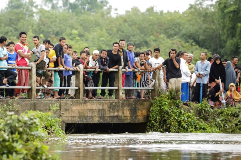 People watch as rescue workers search for two boys who went missing during a flash flood in the southern Thai province of Pattani, on December 6, 2016