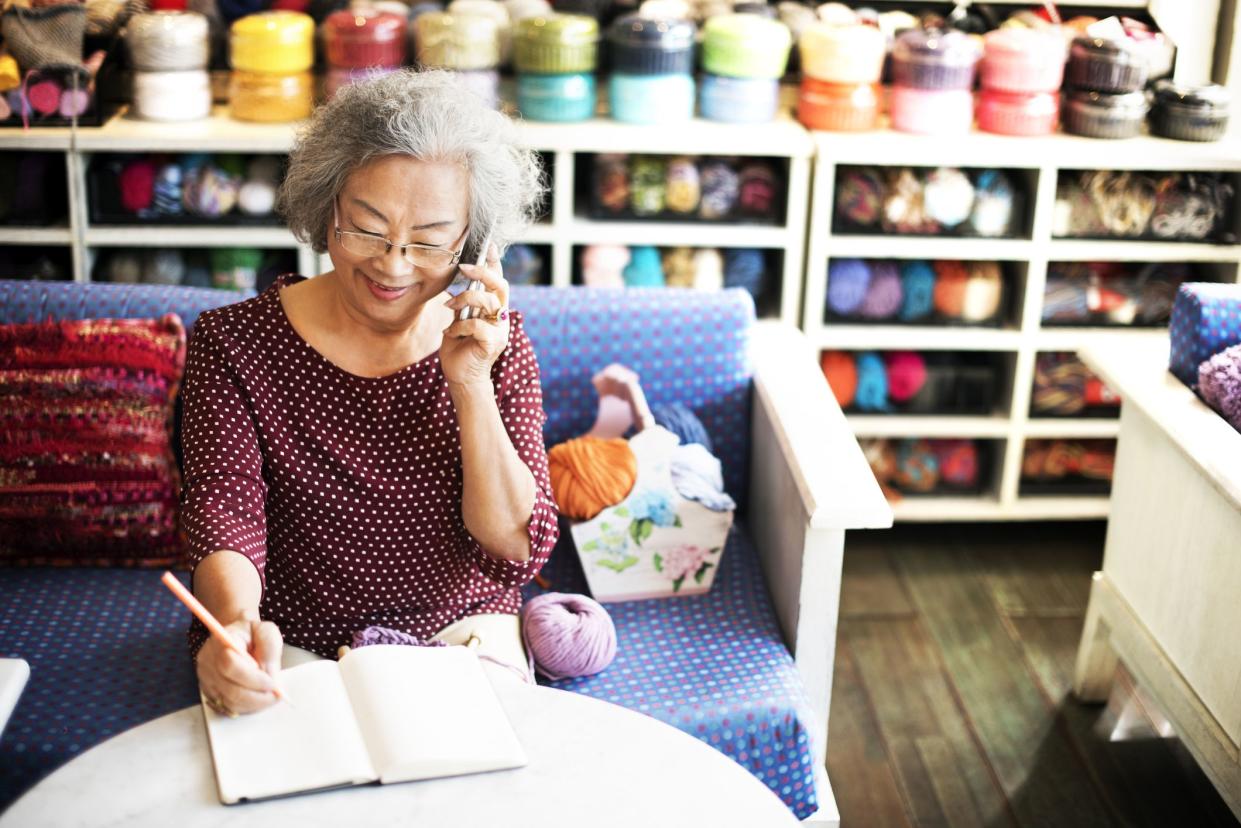 senior woman on phone writing order at knit shop