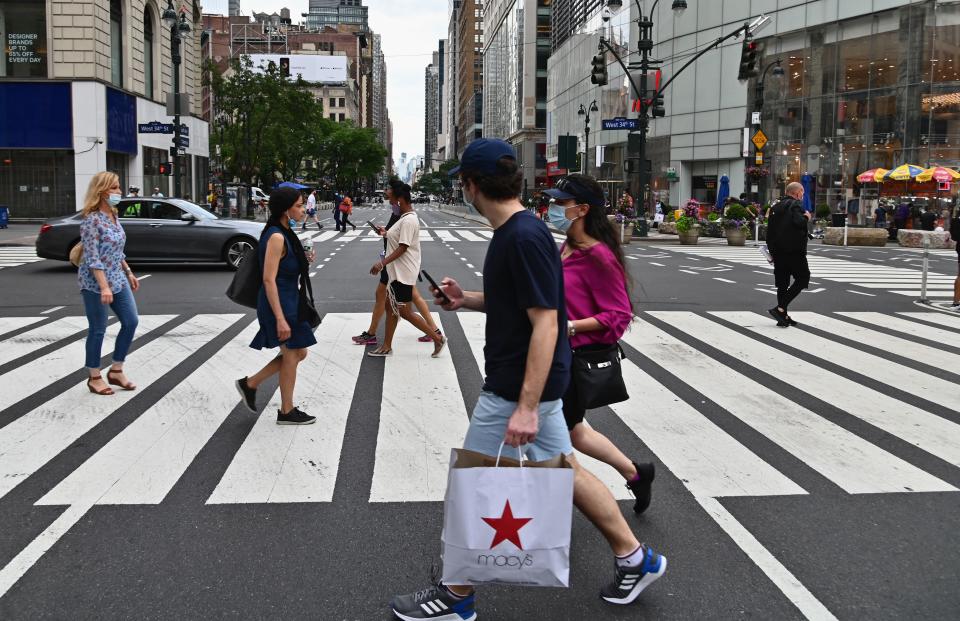 A man wearing facemasks crosses a street carrying a Macy's shopping bag near Herald Square on June 25, 2020 in New York City. - New York businesses opened their doors to returning waves of workers June 22 as the city that was once the epicenter of the global pandemic marked an important milestone in its return to normalcy, even as other US states were seeing an alarming rise in COVID-19 cases. (Photo by Angela Weiss / AFP) (Photo by ANGELA WEISS/AFP via Getty Images)