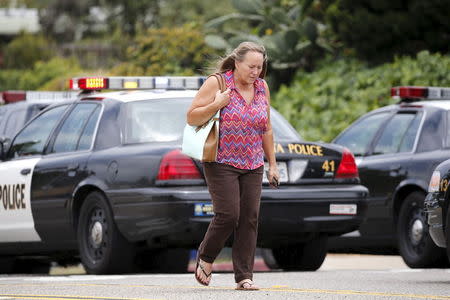 A woman walks past police vehicles after being evacuated from her home near the scene of an armed standoff with a man with a high powered rifle who is holding hostages in Chula Vista, California May 28, 2015. REUTERS/Earnie Grafton