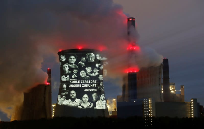 FILE PHOTO: Activists of the environmental organisation Greenpeace project a slogan that reads "No Future in Fossil Fuels" on the cooling tower of RWE coal power plant, in Neurath