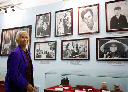 Pham Thi Thuan, My Lai massacre survivor, stands in front of photographs of her and other survivors exhibited at a museum during the 50th anniversary of the My Lai massacre in My Lai village, Vietnam March 15, 2018. REUTERS/Kham