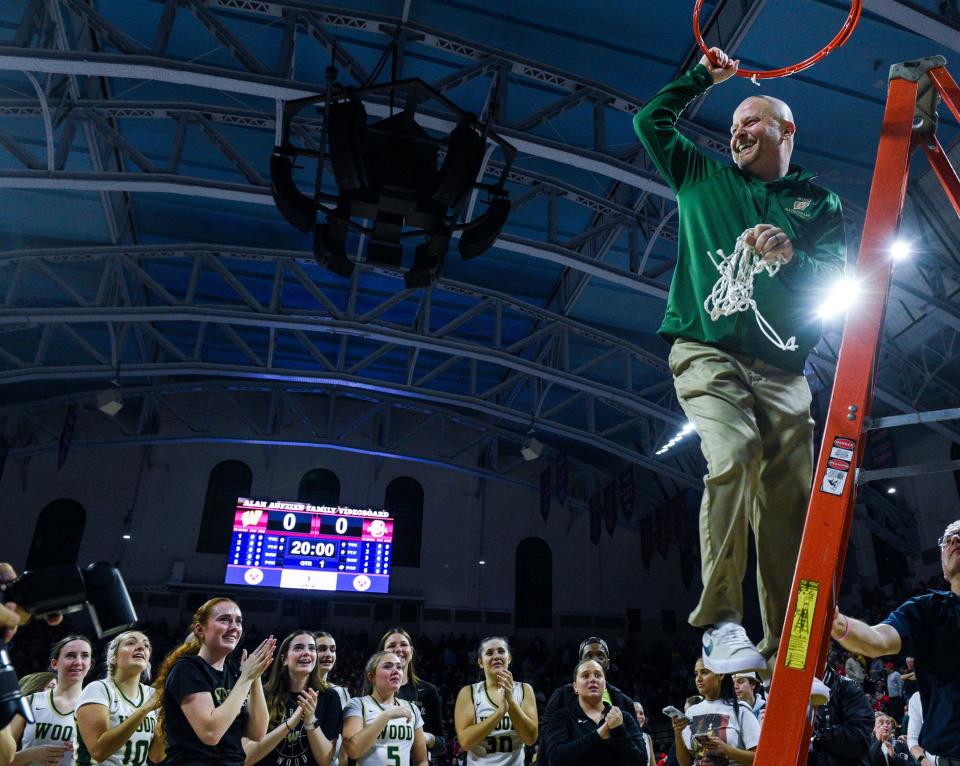 Archbishop Wood's head coach Mike McDonald, right, takes down the rest of the net in celebration of Wood's win over Archbishop Carroll after going into double overtime during the Philadelphia Catholic League girls' basketball championship game in Philadelphia on Monday, Feb. 26, 2024.