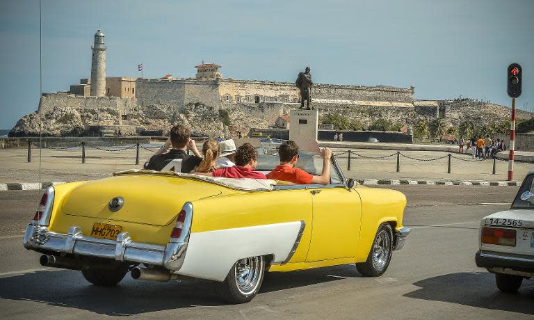 Tourist take a ride in a fully restored Mercury along the coast in Havana on March 18, 2013