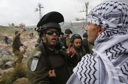 A Palestinian argues with an Israeli policeman during a demonstration against the closure of the main road in Jabaa area south of the West Bank city of Bethlehem January 17, 2015. REUTERS/ Mussa Qawasma