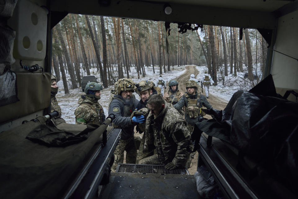 Military medics help a wounded soldier into an evacuation vehicle near Kremenna in the Luhansk region, Ukraine, Monday, Jan. 16, 2023. (AP Photo/LIBKOS)