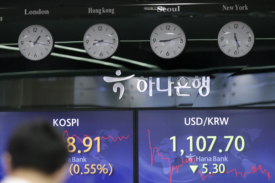 A currency trader walks near the screens showing the Korea Composite Stock Price Index (KOSPI), left, and the foreign exchange rate between U.S. dollar and South Korean won at the foreign exchange dealing room in Seoul, South Korea, Thursday, April 29, 2021. Asian shares rose Thursday and U.S. futures also were higher after President Joe Biden delivered a speech to Congress that outlined ambitious plans for jobs creating spending on early education, child care and other public services.(AP Photo/Lee Jin-man)