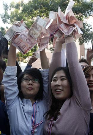 Anti-government protesters hold Thai banknotes to donate to their leader Suthep Thaugsuban during a rally at a major business district in Bangkok December 20, 2013. REUTERS/Kerek Wongsa