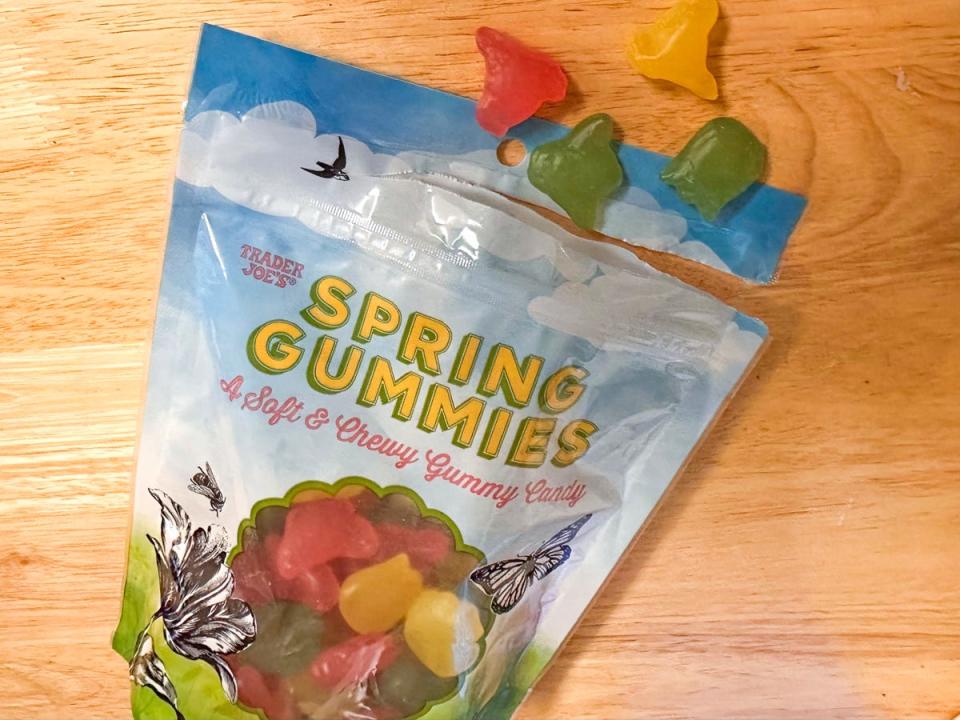 A package with yellow letters spelling out "Spring gummies." The bag has illustrations of grass and a bright-blue sky and a window showing gummy candies inside