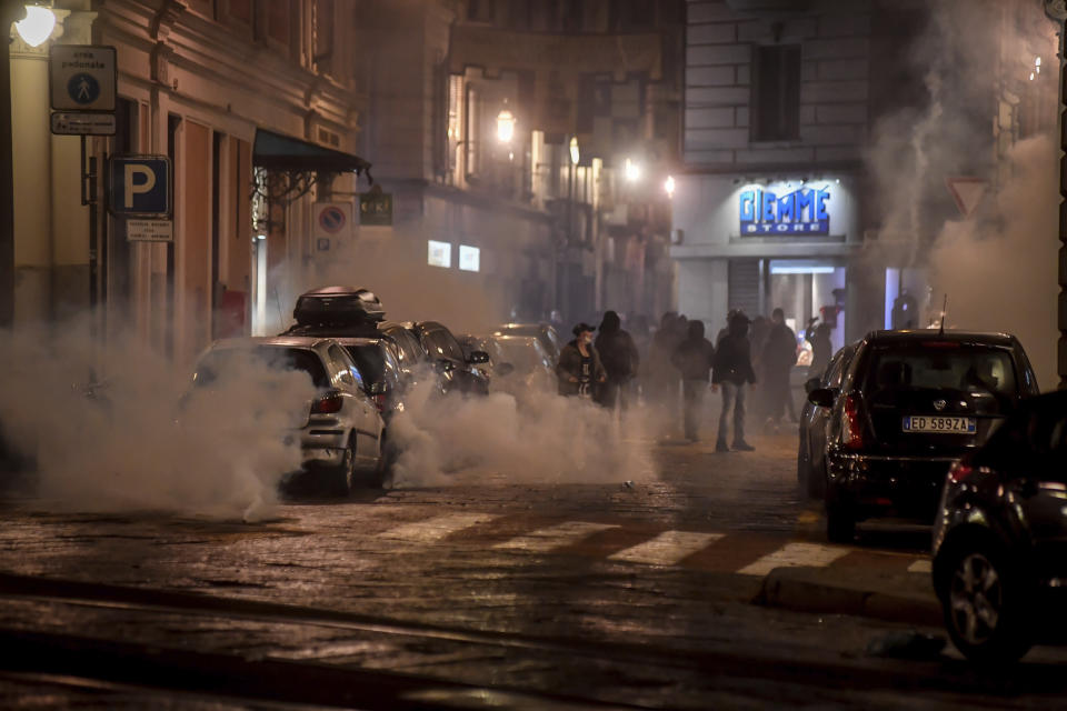 Smoke billows as clashes broke out during a protest against the government restriction measures to curb the spread of COVID-19 in Turin, Italy, Monday, Oct. 26, 2020. Italy's leader has imposed at least a month of new restrictions to fight rising coronavirus infections, shutting down gyms, pools and movie theaters and putting an early curfew on cafes and restaurants. (Claudio Furlan/LaPresse via AP)