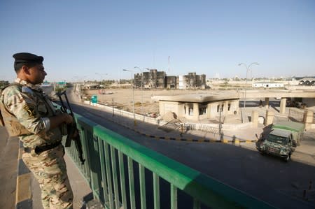 A member of Iraqi police stands guard in front of Maysan Governorate building, which was burnt by demonstrators during a protest over unemployment, corruption and poor public services, in Maysan province, south of Baghdad