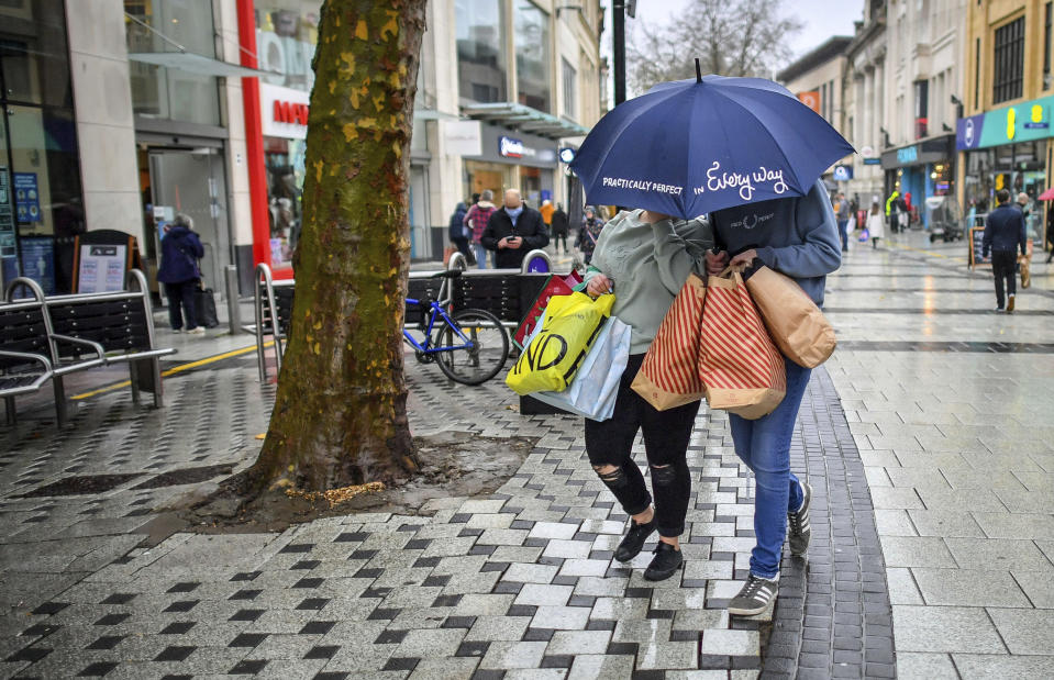 Shoppers loaded with bags and an umbrella to protect against the falling rain, in the centre of Cardiff, Wales, Friday Nov. 20, 2020, where shops are open and people are out in numbers taking advantage of buying nonessential items in the run-up to Christmas. Restrictions across Wales have been relaxed following a two-week "firebreak" lockdown to stem spread of the coronavirus. (Ben Birchall/PA via AP)