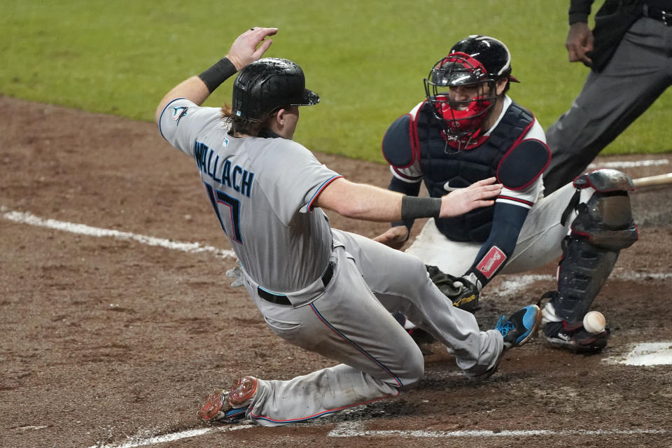 Miami Marlins' Chad Wallach (17) scores on a Jon Berti double as the ball gets away from Atlanta Braves catcher Travis d'Arnaud during the sixth inning of a baseball game Thursday, Sept. 24, 2020, in Atlanta. (AP Photo/John Bazemore)