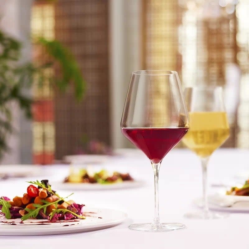 Wine glasses filled with red and white wine next to plates of food