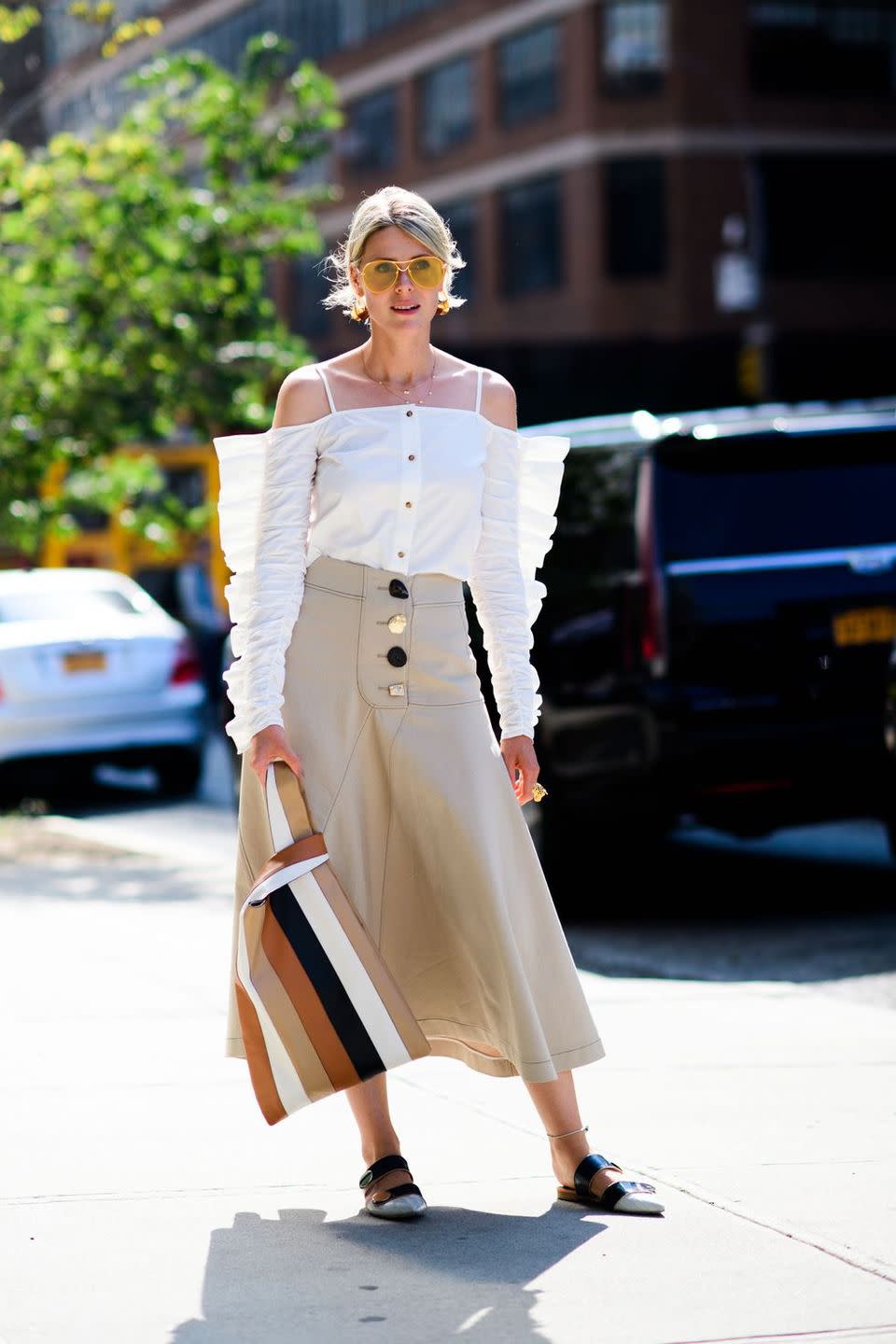 a model wears a white blouse and a khaki skirt