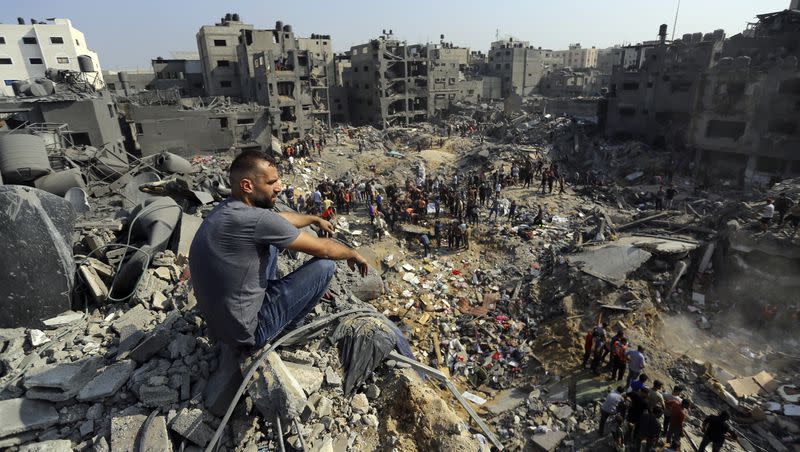 A man sits on the rubble as others wander among debris of buildings that were targeted by Israeli airstrikes in Jabaliya refugee camp, northern Gaza Strip, on Wednesday, Nov. 1, 2023.