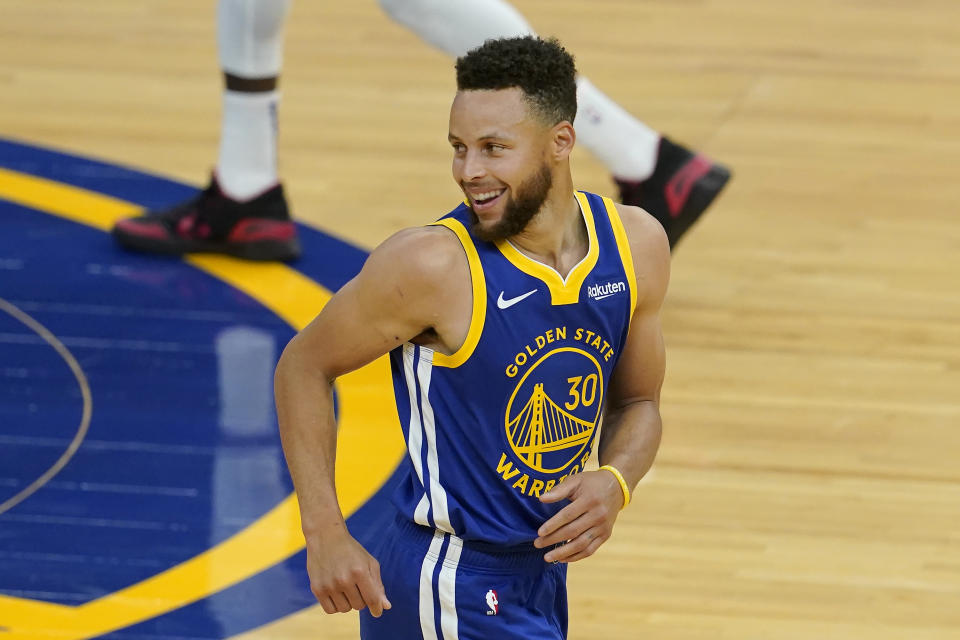 Stephen Curry smiles after scoring during a game.