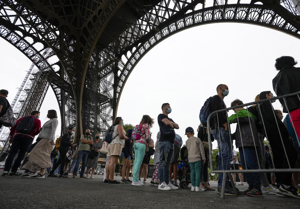 Visitor line up at the Eiffel Tower in Paris, Friday, July 16, 2021. The Eiffel Tower is reopening Friday for the first time in nine months, just as France faces new virus rules aimed at taming the fast-spreading delta variant. The "Iron Lady" was ordered shut in October as France battled its second surge of the virus. (AP Photo/Michel Euler)