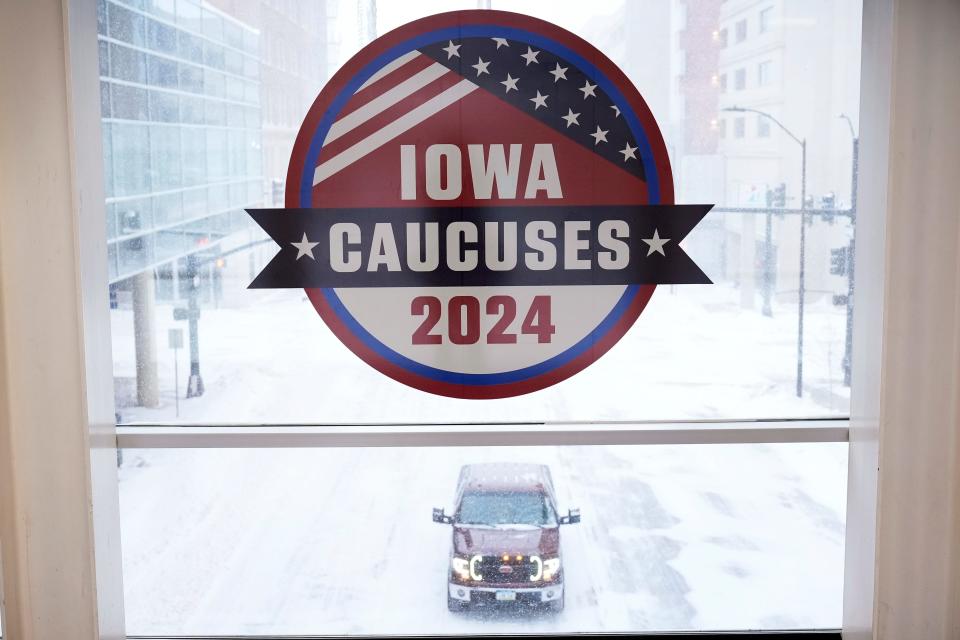 A pickup truck is driven down a snow covered road under an Iowa Caucus sign, Friday, Jan. 12, 2024, in downtown Des Moines, Iowa.