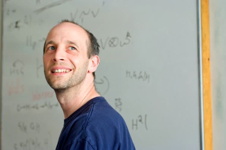 a man smiling in front of a whiteboard