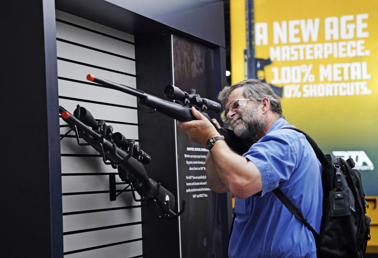 A visitor checks out a rifle at the annual meeting Friday.  (Allison Dinner for NBC News)