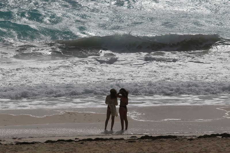 Tourists stand at a beach as Hurricane Zeta approaches Cancun