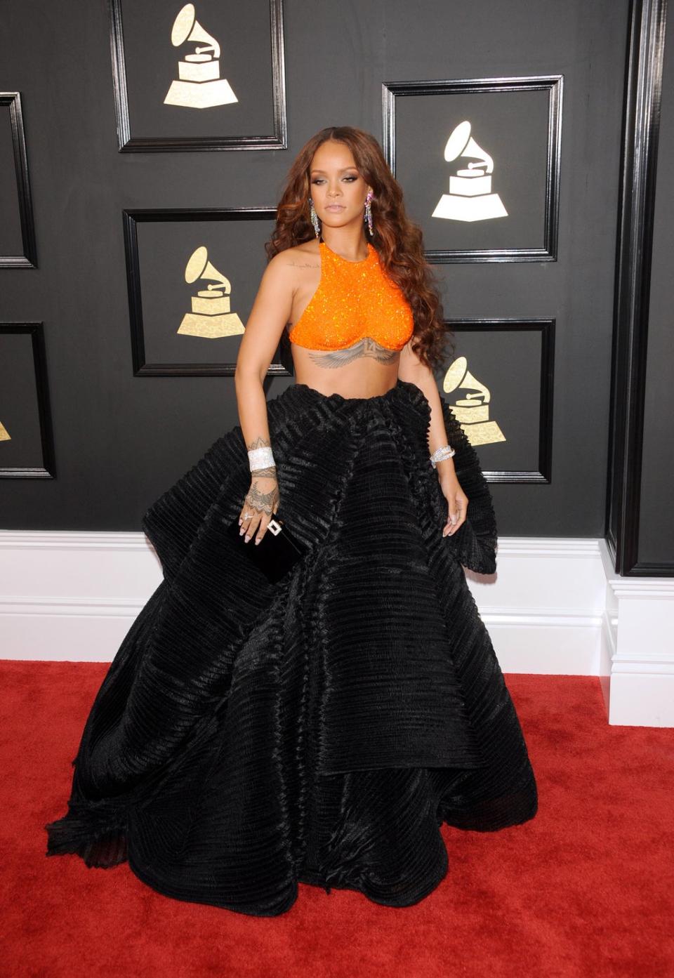 In 2017, Rihanna showcased a modern spin on red carpet fashion, wearing an ensemble by Armani Privé featuring a large, black, ballgown skirt and an orange, embellished crop top. One of the most memorable moments of the evening came when the singer revealed her bedazzled flask while sitting in the audience (Getty)