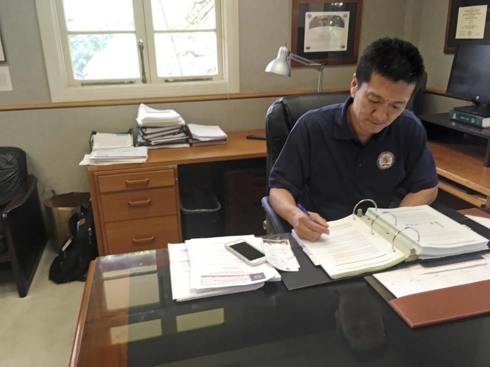 In this Friday, March 10, 2017 photo, Hawaii Attorney General Douglas Chin works in his office in Honolulu. Hawaii was the first state to file a lawsuit challenging President Donald Trump's revised travel ban. For Chin, the son of Chinese immigrants, fighting the travel ban is personal. (AP Photo/Jennifer Sinco Kelleher).