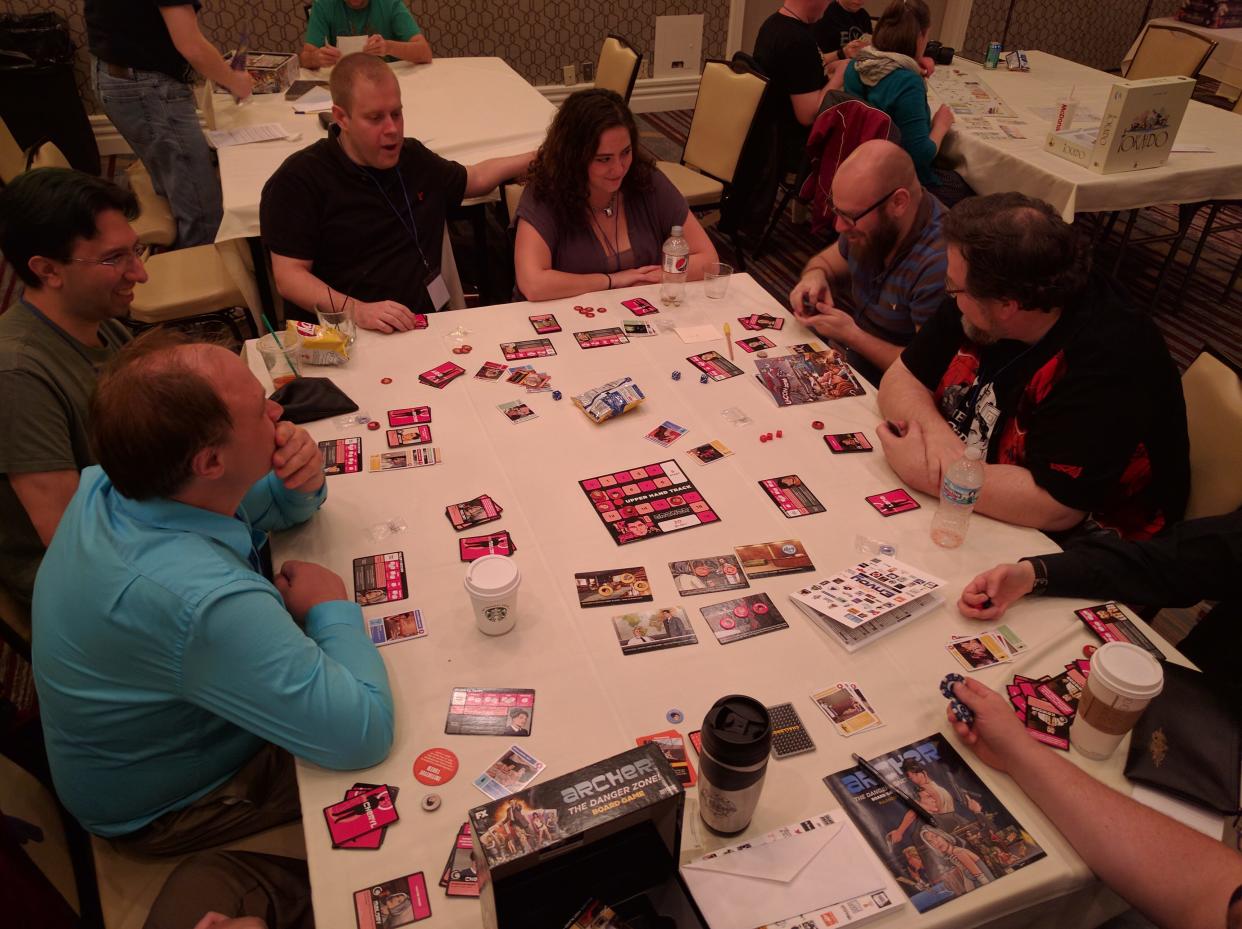 A group of attendees playing the Archer: The Danger Zone board game at a previous U-Con Convention.
