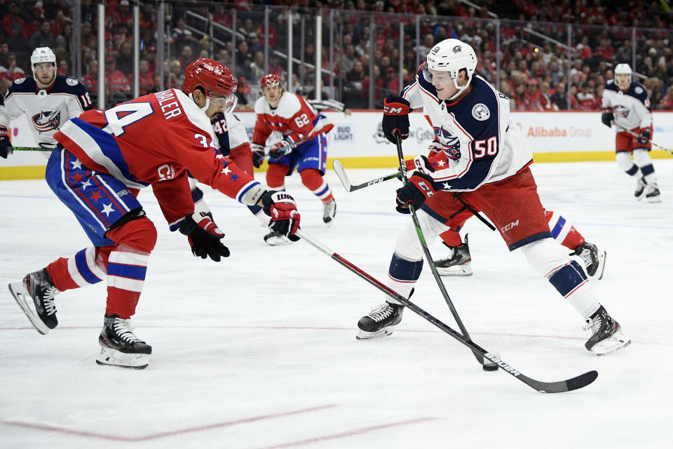Columbus Blue Jackets left wing Eric Robinson (50) skates with the puck next to Washington Capitals defenseman Jonas Siegenthaler (34) during the first period of an NHL hockey game Friday, Dec. 27, 2019, in Washington. (AP Photo/Nick Wass)