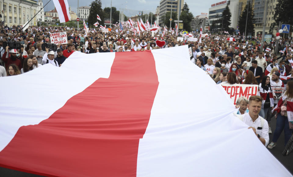 Protester carry a huge old Belarusian national flag during an opposition rally to protest the official presidential election results in Minsk, Belarus, Sunday, Sept. 6, 2020. Sunday's demonstration marked the beginning of the fifth week of daily protests calling for Belarusian President Alexander Lukashenko's resignation in the wake of allegedly manipulated elections. (AP Photo/TUT.by)