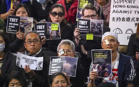 Demonstrators hold placards and wear eye patches in solidarity with those allegedly injured by police - Credit: David Gray/Bloomberg