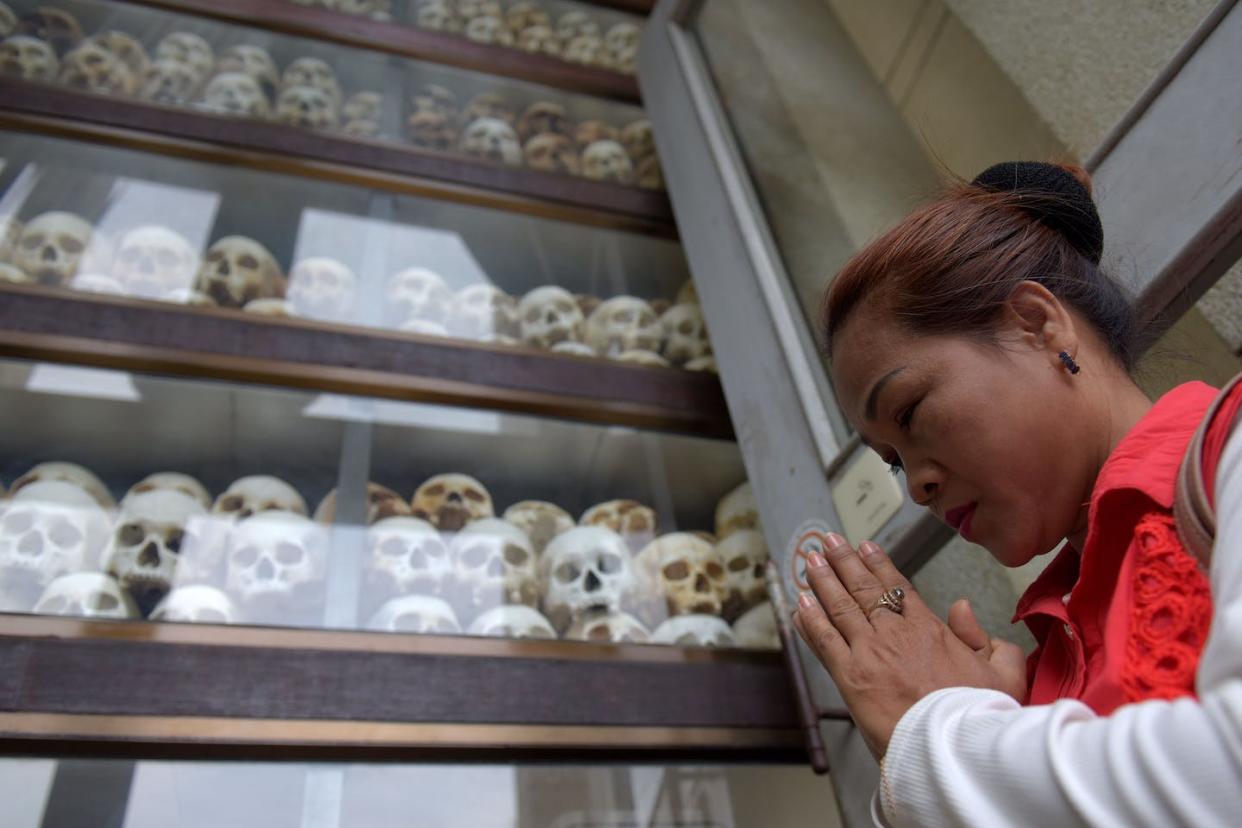 A woman prays in front of skulls at a memorial in Phnom Penh, Cambodia, marking the genocide that happened under the Khmer Rouge regime in the 1970s. <a href="https://www.gettyimages.com/detail/news-photo/woman-prays-in-front-of-skulls-at-the-choeung-ek-memorial-news-photo/960278782?adppopup=true" rel="nofollow noopener" target="_blank" data-ylk="slk:Tang Chhin Sothy/AFP via Getty Images;elm:context_link;itc:0;sec:content-canvas" class="link ">Tang Chhin Sothy/AFP via Getty Images </a>