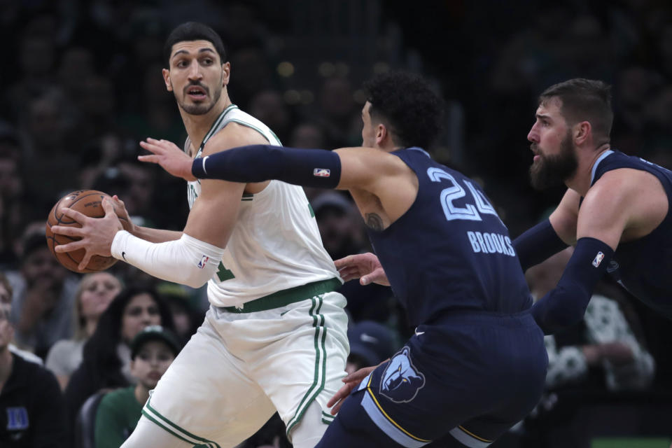 Boston Celtics center Enes Kanter, left, looks to pass while covered by Memphis Grizzlies guard Dillon Brooks (24) and center Jonas Valanciunas, right, during the first half of an NBA basketball game in Boston, Wednesday, Jan. 22, 2020. (AP Photo/Charles Krupa)